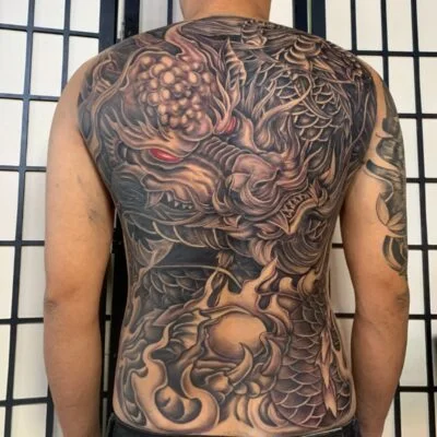 Hình xăm rồng full lưng trên lưng nam giới với chi tiết vảy và mắt rồng đỏ.