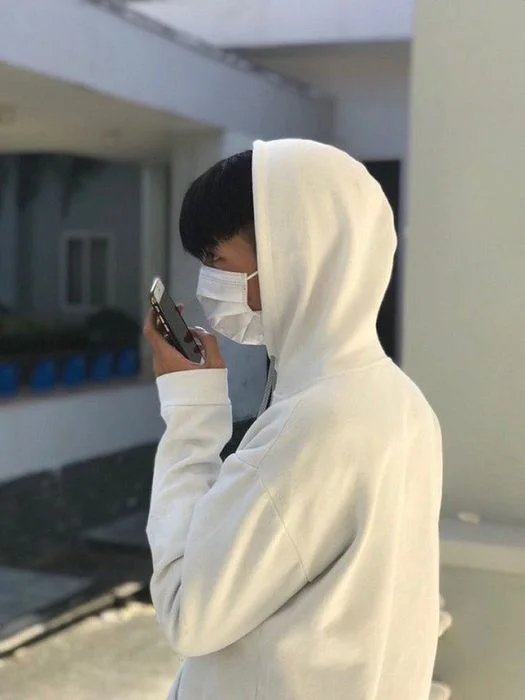 Trai đẹp che mặt khẩu trang sử dụng điện thoại