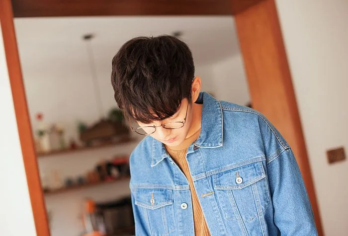 Chàng trai mặc áo denim che mặt khi đang cúi xuống trong chủ đề trai đẹp che mặt